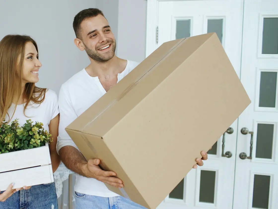 Couple portant un carton de déménagement dans son nouvel appartement